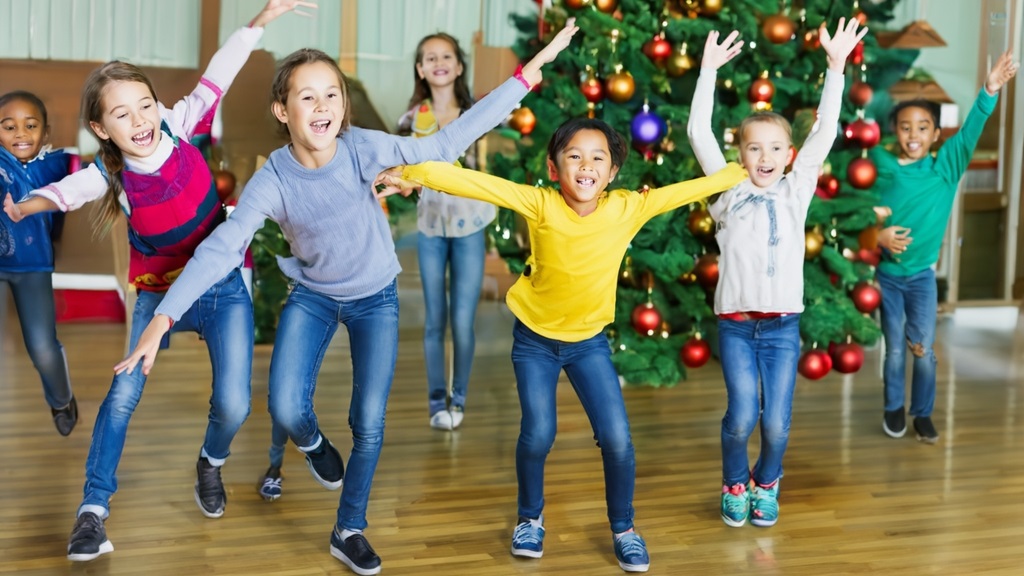 Glada barn som dansar framför en julgran